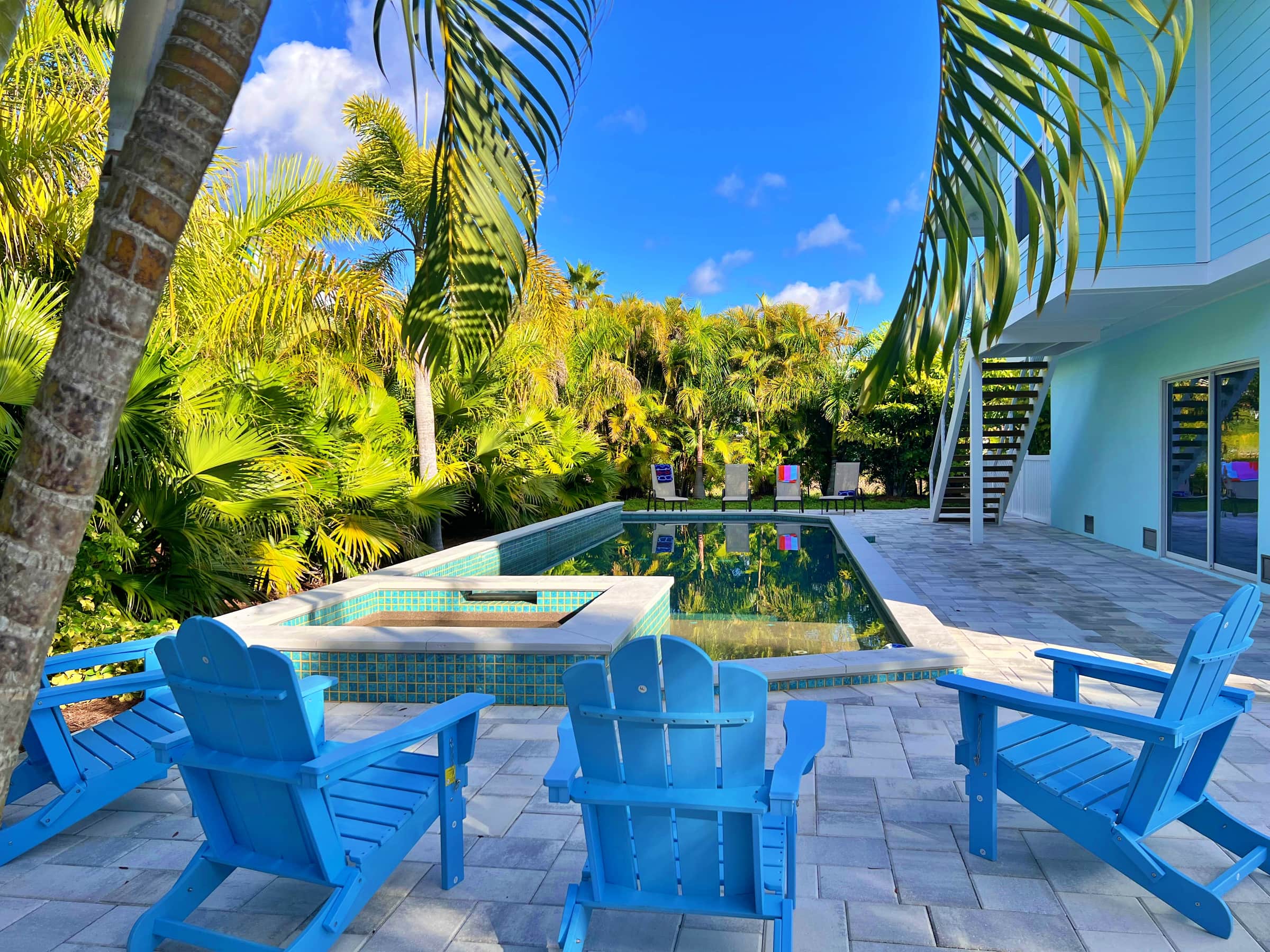 Backyard pool with blue lounge chairs among palms at SkyWater Retreat, a home we look after